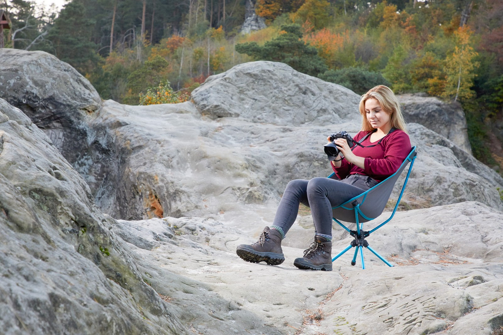 Kvinna med kamera sittande på en klippa i en campingstol från Uquip